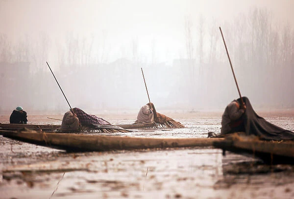 Kashmiri fishermen cover their heads and part of their boats with blankets