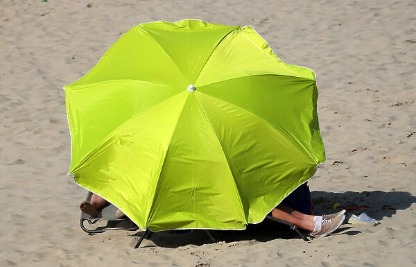 People stay under umbrellas during a hot summer day in Blankenberge