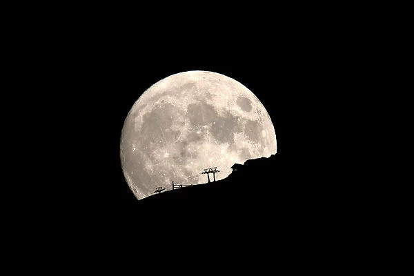 A ski lift at the Kalavrita ski centre on Mount Helmos is silhouetted as the moon rises