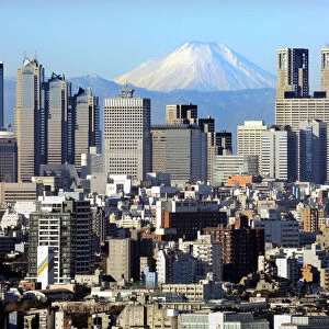 Japans Mt Fuji, covered with snow, is seen through Shinjuku skyscrapers in Tokyo