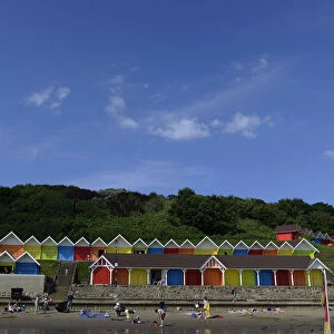 People relax in front of beach huts in the North Bay in Scarborough