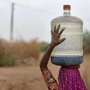 Village woman carries container filled with drinking water supplied by the government-run