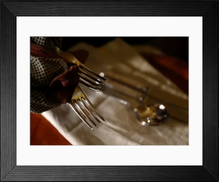 Framed Print : A woman polishes silver cutlery at her home in Valletta