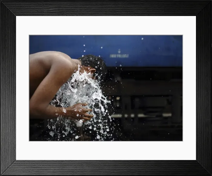 Framed Print : A boy washes using a pipe that supplies water for trains at Old Delhi railway station Framed Print : A boy washes using a pipe that supplies water for trains at Old Delhi railway station