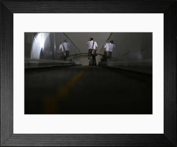 Framed Print : A man rides an escalator at a subway station in Beijing Framed Print : A man rides an escalator at a subway station in Beijing