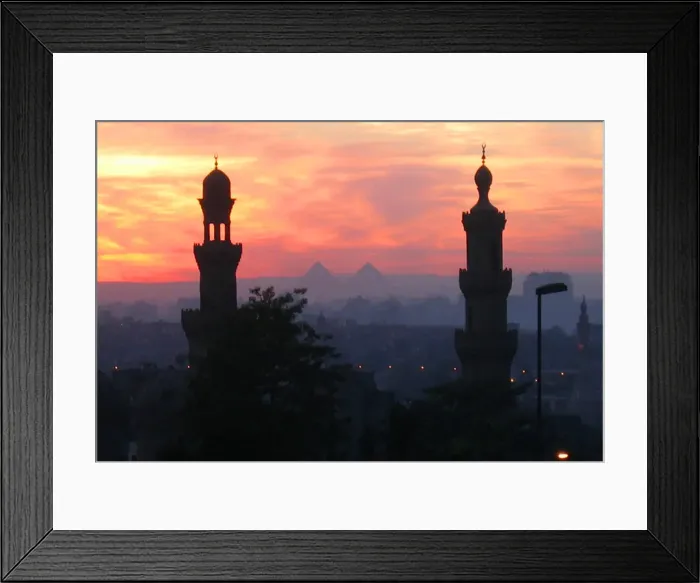Framed Print : Pyramids of Giza appear between two minarets during a warm winter sunset in Cairo Framed Print : Pyramids of Giza appear between two minarets during a warm winter sunset in Cairo