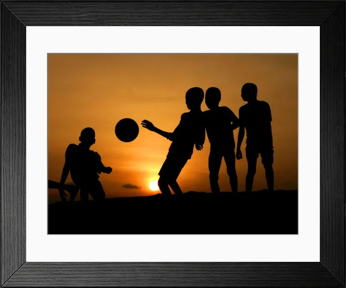 Framed Print : Children playing soccer are silhouetted at sunset in Nigerias main city of Lago Framed Print : Children playing soccer are silhouetted at sunset in Nigerias main city of Lago