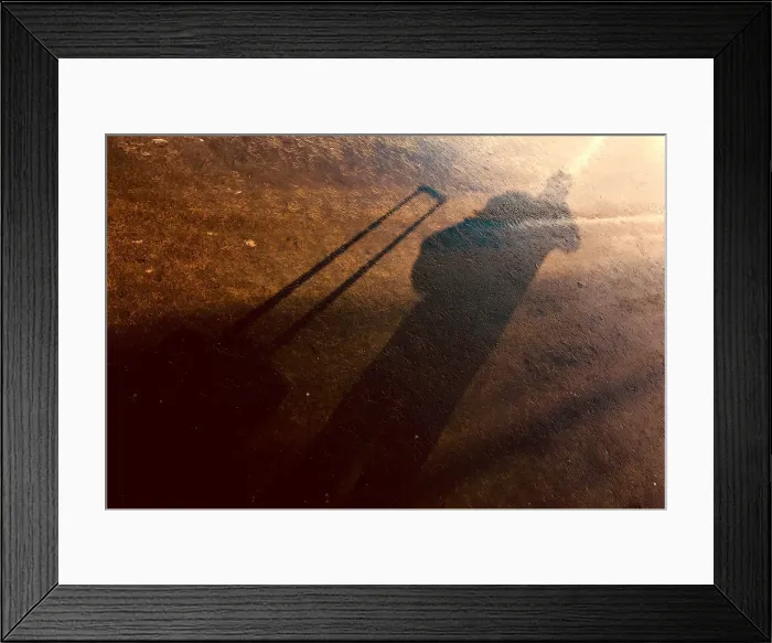 Framed Print : The shadow of a photographer and his equipment bag can be seen on a footpath after a storm at Samara Stadium Framed Print : The shadow of a photographer and his equipment bag can be seen on a footpath after a storm at Samara Stadium
