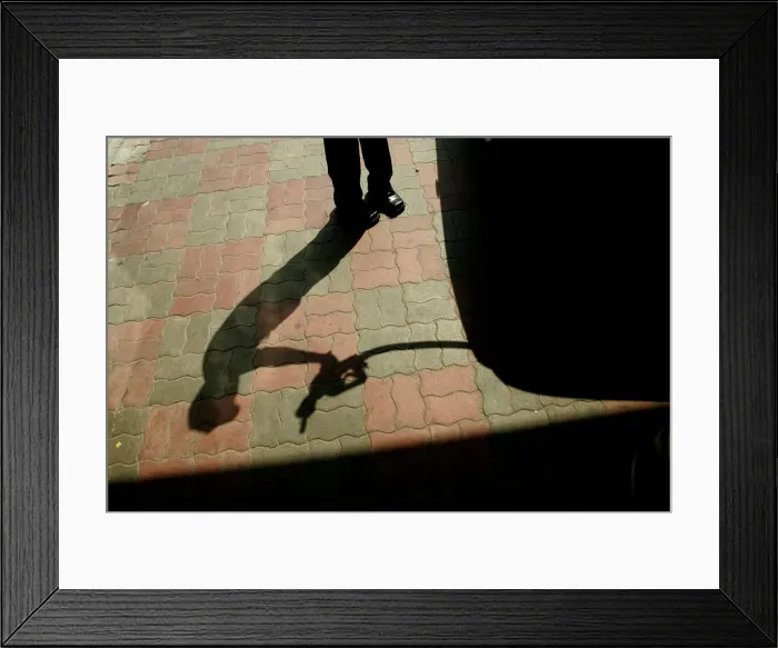 Framed Print : An Indian worker lifts a petrol nozzle at a petrol pump in New Delhi