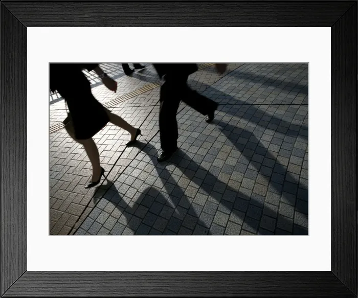 Framed Print : Pedestrians cast shadows as they walk on a street in Tokyo Framed Print : Pedestrians cast shadows as they walk on a street in Tokyo