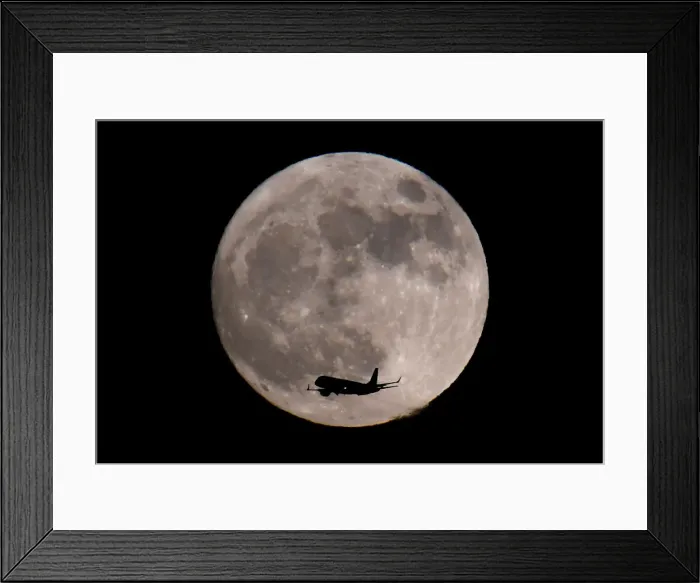 Framed Print : A passenger plane, with a supermoon full moon seen behind, makes its final landing