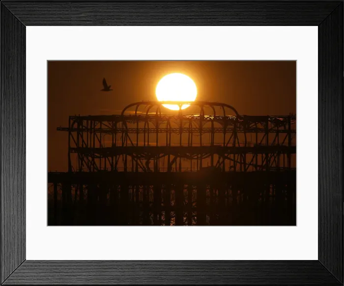 Framed Print : The sun sets behind the old West Pier in Brighton, southern England