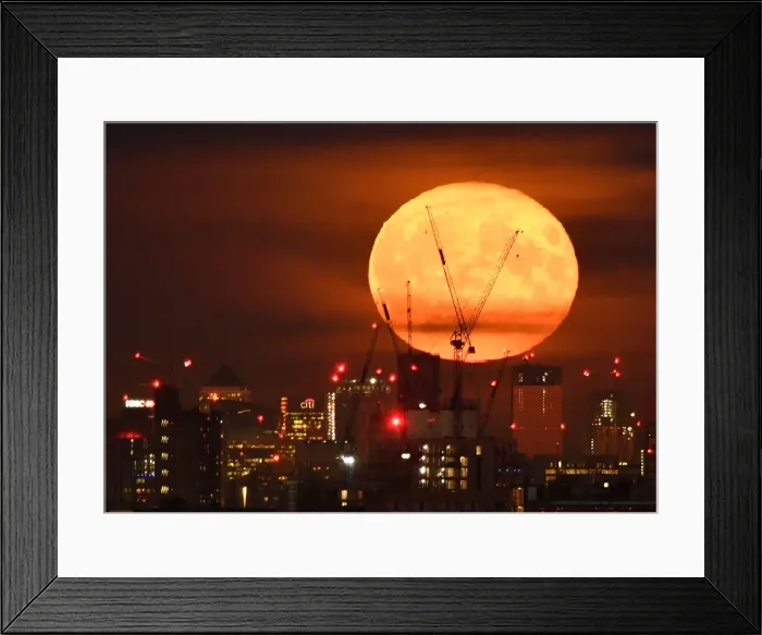 Framed Print : The full moon is seen rising behind skyscrapers at Canary Wharf and the London skyline Framed Print : The full moon is seen rising behind skyscrapers at Canary Wharf and the London skyline