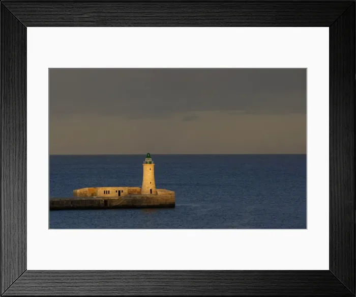 Framed Print : A lighthouse is seen at dusk in a harbour in Valletta