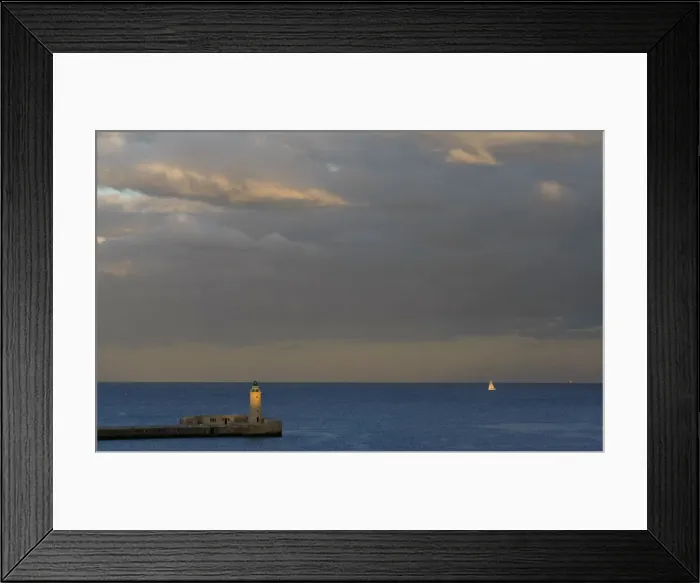 Framed Print : A lighthouse is seen at dusk in a harbour in Valletta