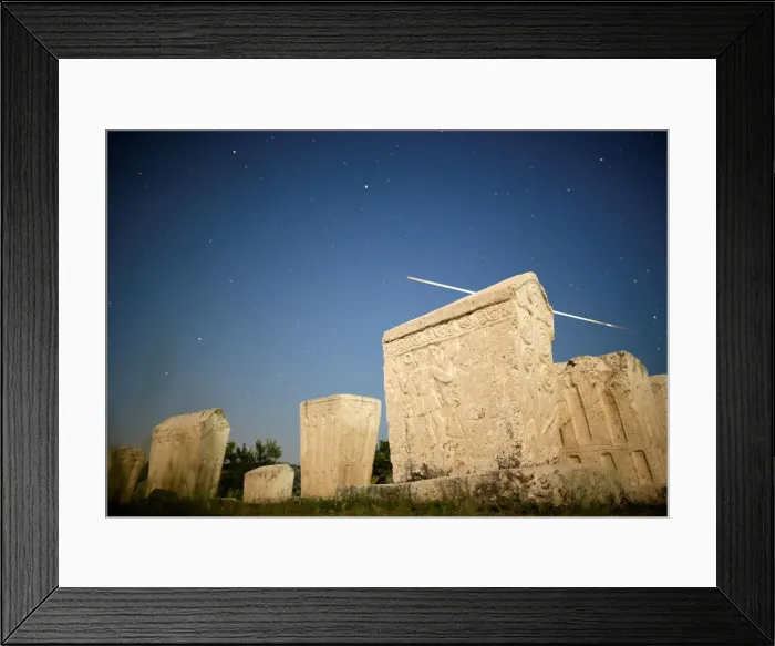 Framed Print : A meteor streaks past stars in the night sky above medieval tombstones during