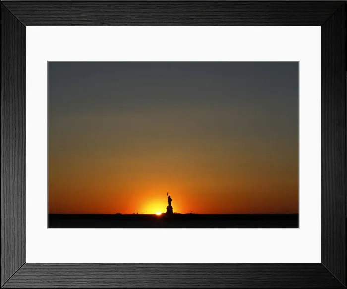 Framed Print : The sun sets behind the Statue of Liberty in New York Framed Print : The sun sets behind the Statue of Liberty in New York
