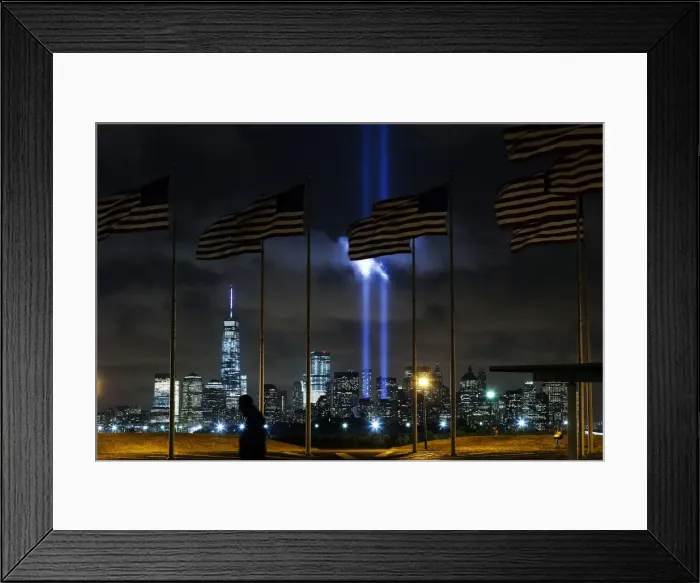 Framed Print : Man walks past as the Tribute in Light is illuminated on the skyline of lower Manhattan