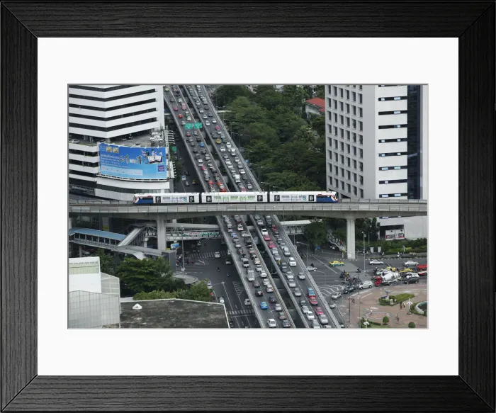 Framed Print : A skytrain passes over vehicles on the road during rush hour in Bangkok Framed Print : A skytrain passes over vehicles on the road during rush hour in Bangkok