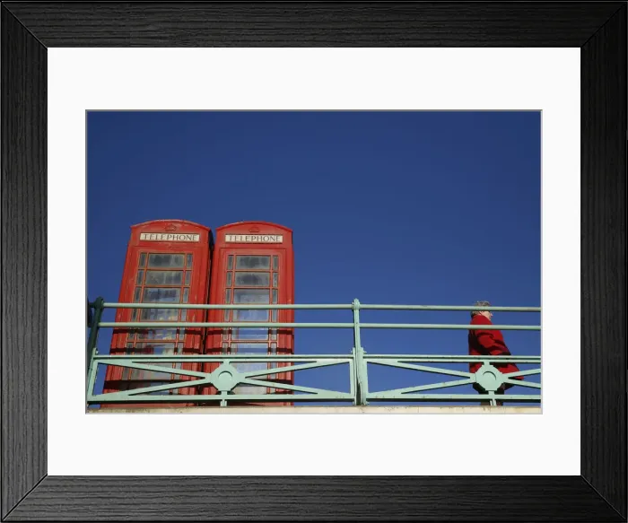 Framed Print : A woman stands next to two traditional telephone boxes in Brighton Framed Print : A woman stands next to two traditional telephone boxes in Brighton