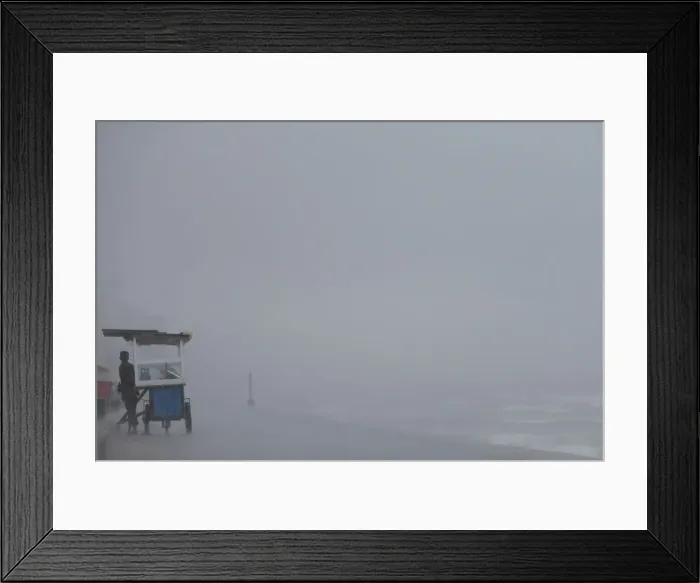 Framed Print : A vendor hides from the rain behind his food cart during a wet day in Colombo