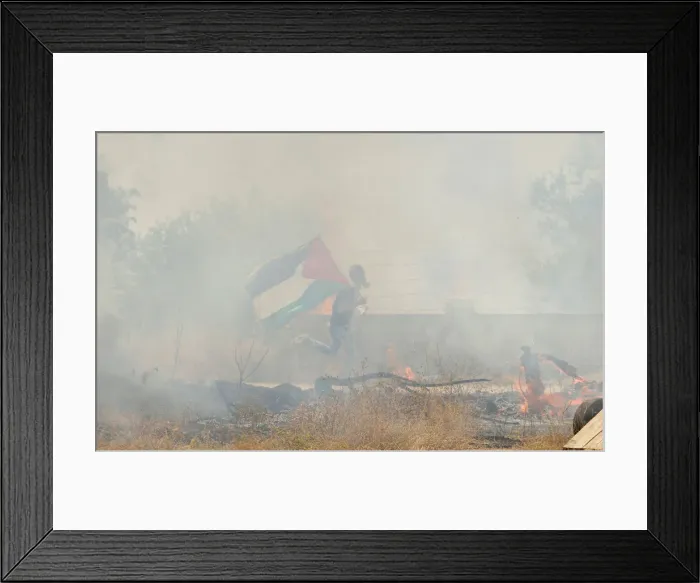 Framed Print : Protester holding a Palestinian flag runs for cover from tear gas fired by Israeli troops Framed Print : Protester holding a Palestinian flag runs for cover from tear gas fired by Israeli troops