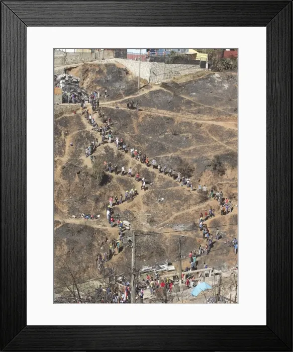 Framed Print : Volunteers form a line as they pass down debris from burned houses after a fire burned Framed Print : Volunteers form a line as they pass down debris from burned houses after a fire burned