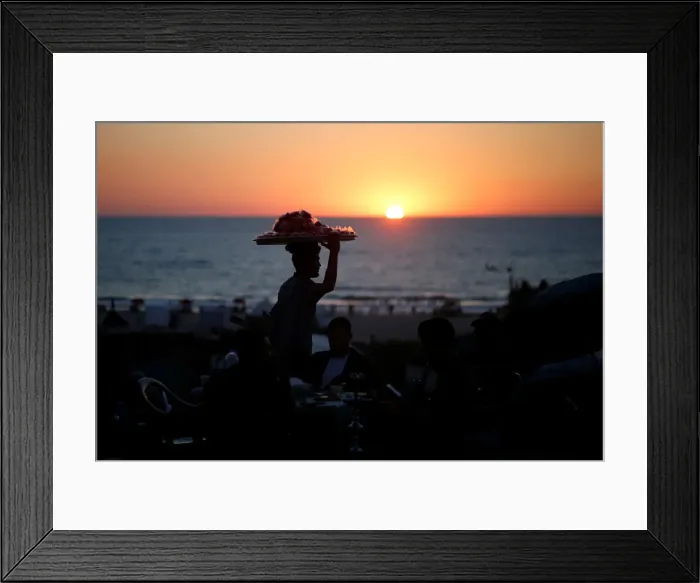 Framed Print : A vendor sells candied apples during the sunset on the beach in Gaza City