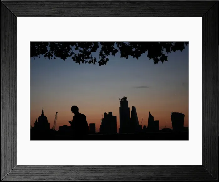 Framed Print : A man walks past the city of London financial district as dawn breaks in London Framed Print : A man walks past the city of London financial district as dawn breaks in London