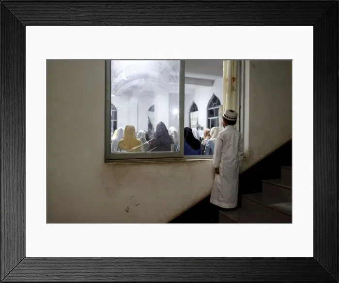 Framed Print : A boy looks in through a window as he and other worshippers pray on Laylat al-Qadr during Framed Print : A boy looks in through a window as he and other worshippers pray on Laylat al-Qadr during