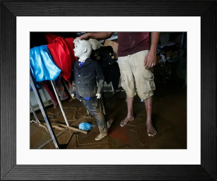 Framed Print : A man holds a muddied mannequin inside his tailoring shop, which was affected by floods Framed Print : A man holds a muddied mannequin inside his tailoring shop, which was affected by floods