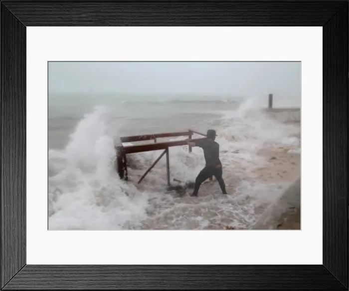 Framed Print : A man tries to salvage a table belonging to his restaurant before the arrival of Framed Print : A man tries to salvage a table belonging to his restaurant before the arrival of