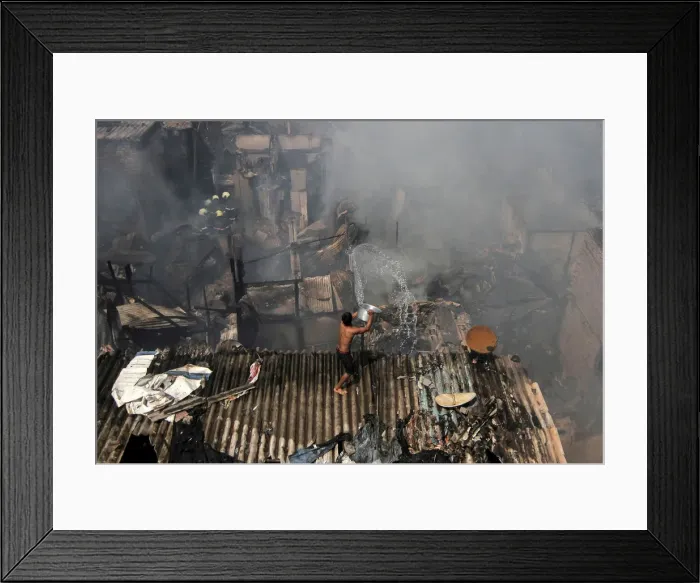 Framed Print : A man pours water to douse a fire that broke out in a slum in Mumbai Framed Print : A man pours water to douse a fire that broke out in a slum in Mumbai
