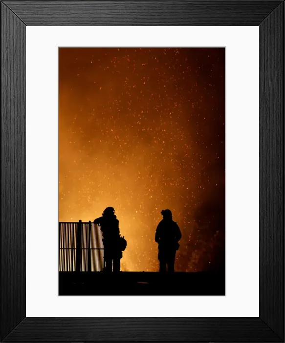 Framed Print : Burning embers swirl around firefighters as they stand guard at a home while battling
