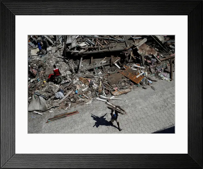 Framed Print : A man carries wooden planks salvaged from the rubble of a destroyed houses after Framed Print : A man carries wooden planks salvaged from the rubble of a destroyed houses after