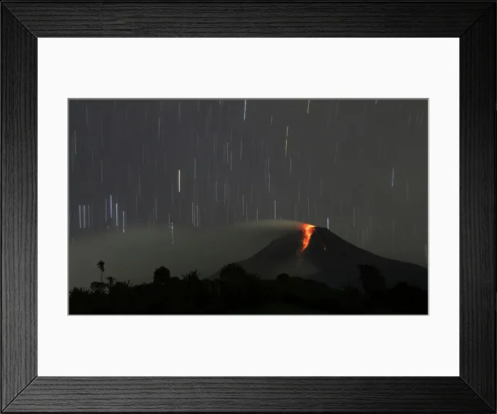 Framed Print : A long exposure photo shows star trails as Mount Sinabung volcano spews hot lava as seen Framed Print : A long exposure photo shows star trails as Mount Sinabung volcano spews hot lava as seen