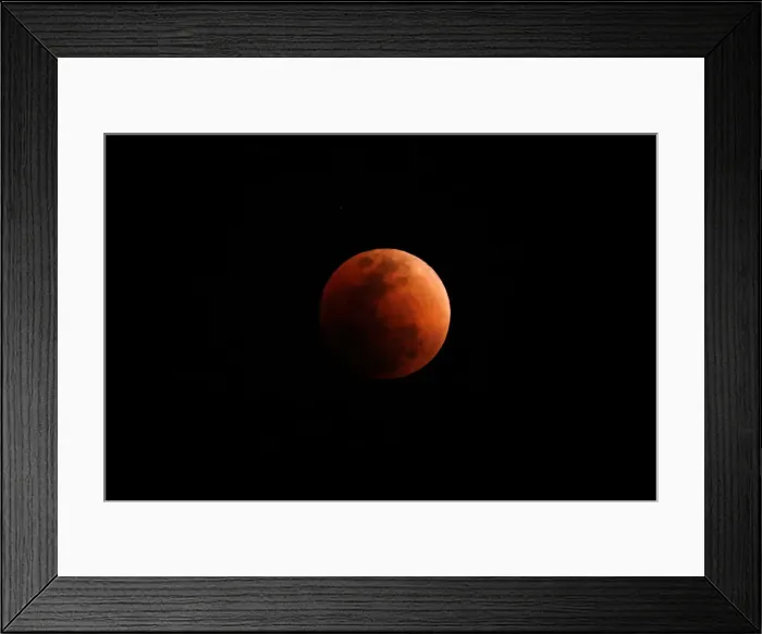 Framed Print : A super blood blue moon is seen during an eclipse, behind an office building in Hong