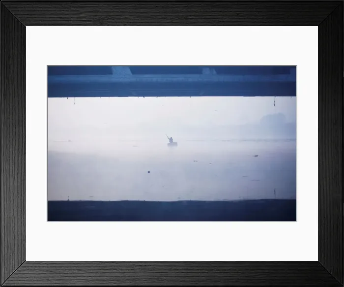 Framed Print : A man paddles a handmade boat across the Yamuna river on a foggy winter morning in New