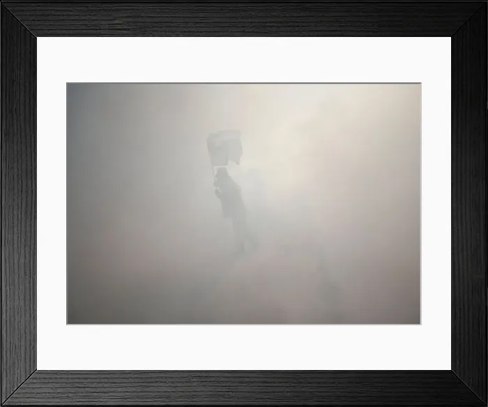 Framed Print : Protester holds a Palestinian flag as he stands amidst tear gas fired by Israeli troops
