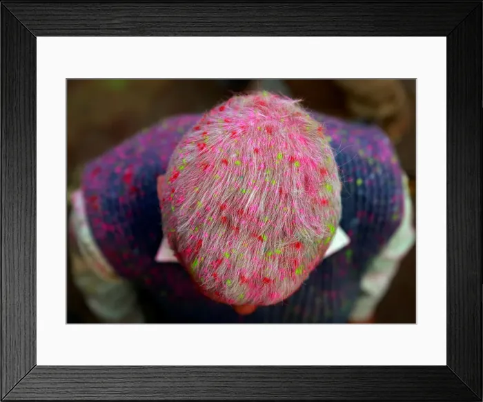 Framed Print : A Hindu devotee is covered in coloured powder as he stands outside a temple during