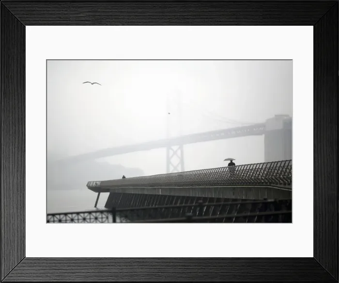 Framed Print : A man walks beneath an umbrella along Pier 14 near the San Francisco Oakland Bay Bridge Framed Print : A man walks beneath an umbrella along Pier 14 near the San Francisco Oakland Bay Bridge