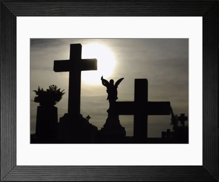 Framed Print : The sun is pictured behind a cross on a gravestone on the eve of All Saints Day