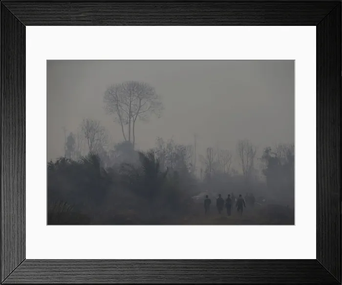 Framed Print : Indonesian soldiers and policemen walk for a break after spraying water on burned palm