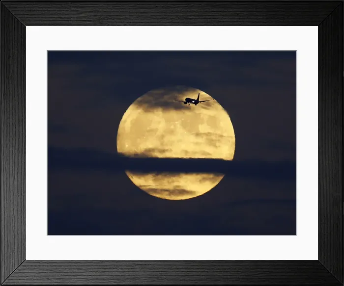 Framed Print : A commercial airliner crosses the path of a rising full moon as it comes in to land