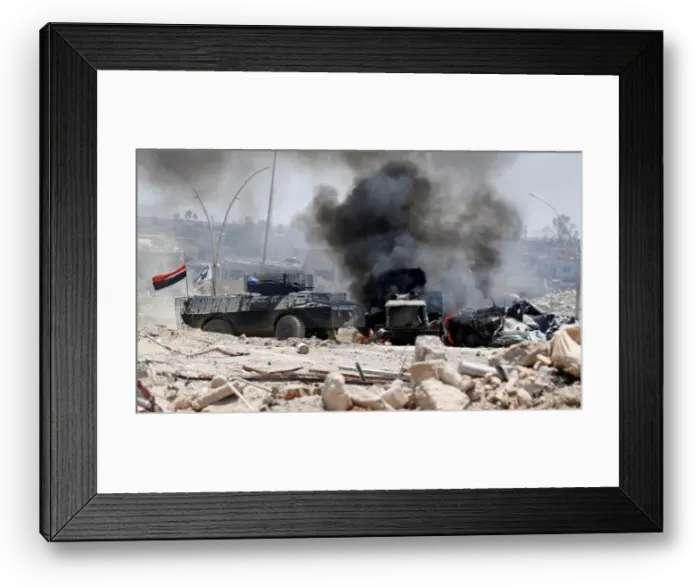 Framed Print : An Iraqi military armoured fighting vehicle (AFV) drives past a burning Iraqi military