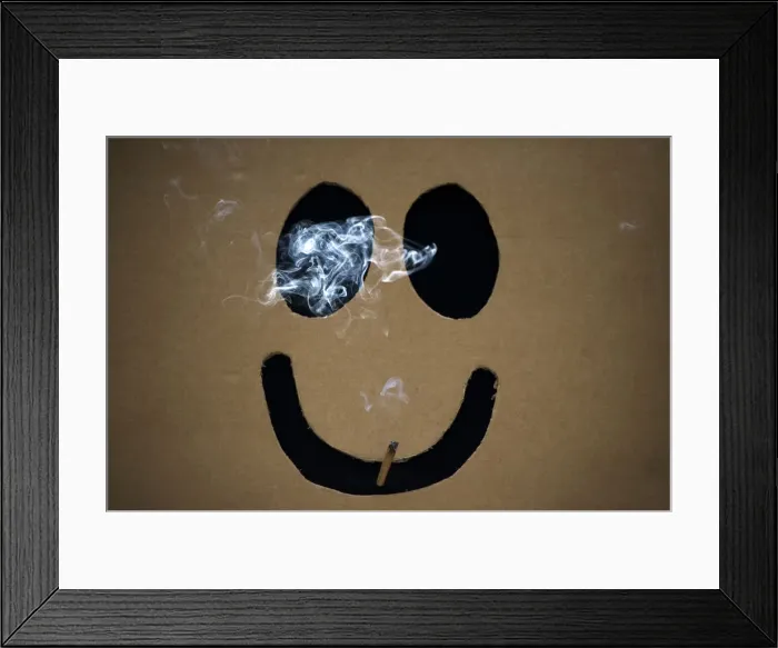 Framed Print : A man smokes a marijuana joint inside a box with a happy face cut out before The Global Framed Print : A man smokes a marijuana joint inside a box with a happy face cut out before The Global