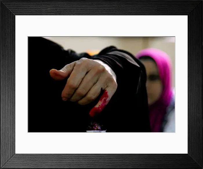 Framed Print : An Egyptian woman has her finger stained with ink after casting her vote during the first