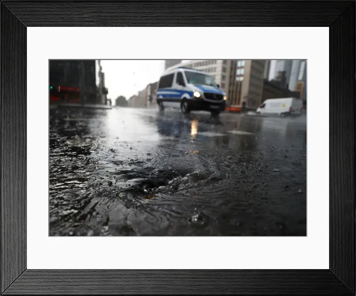 Framed Print : A police vehicle drives on a street during heavy rain in Frankfurt Framed Print : A police vehicle drives on a street during heavy rain in Frankfurt