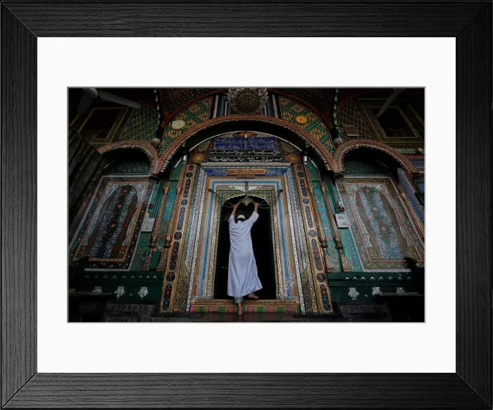 Framed Print : A Muslim man touches an ornament, engraved with verses from the Koran