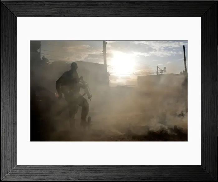 Framed Print : Police officer tries to extinguish fire set by demonstrators in Cidade de Deus slum Framed Print : Police officer tries to extinguish fire set by demonstrators in Cidade de Deus slum